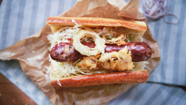 Hot dog z kiełbasą z dziczyzny, sosem tatarskim i krążkami cebuli