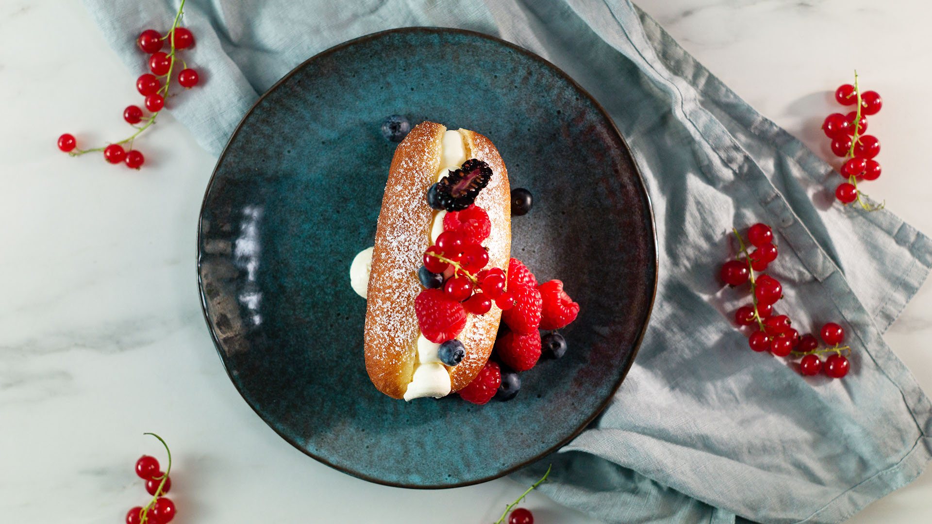 Podłużne pączki ze śmietaną i owocami